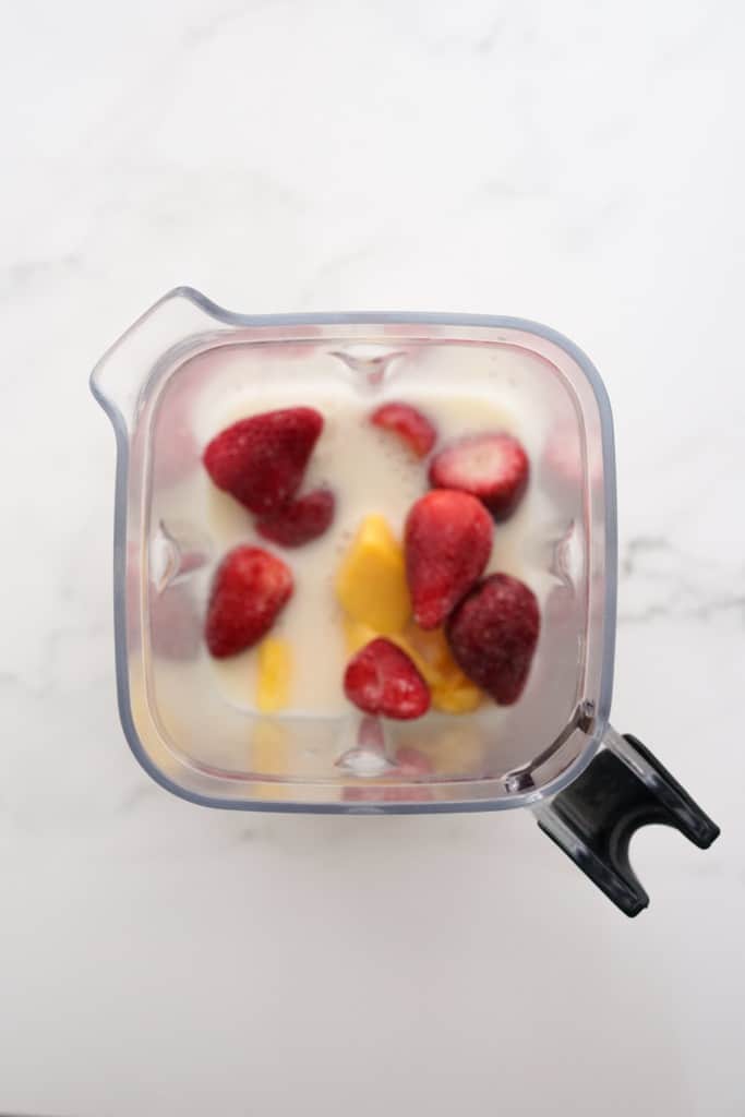 Almond milk, frozen strawberries and frozen mangos in blender