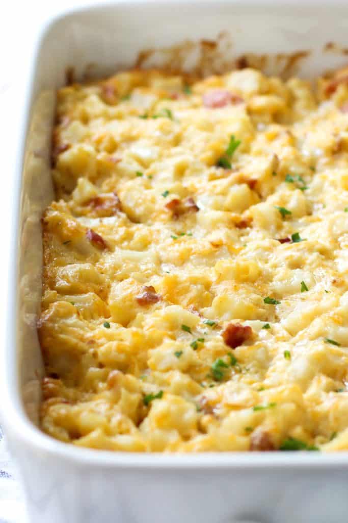 Cheesy Bacon Potato Casserole with garnishes on the side