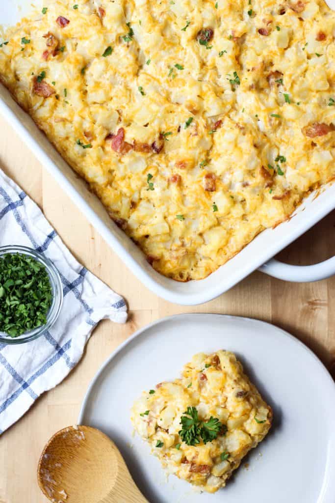 top down view of potato bacon casserole in a rectangular dish and scooped out on a plate