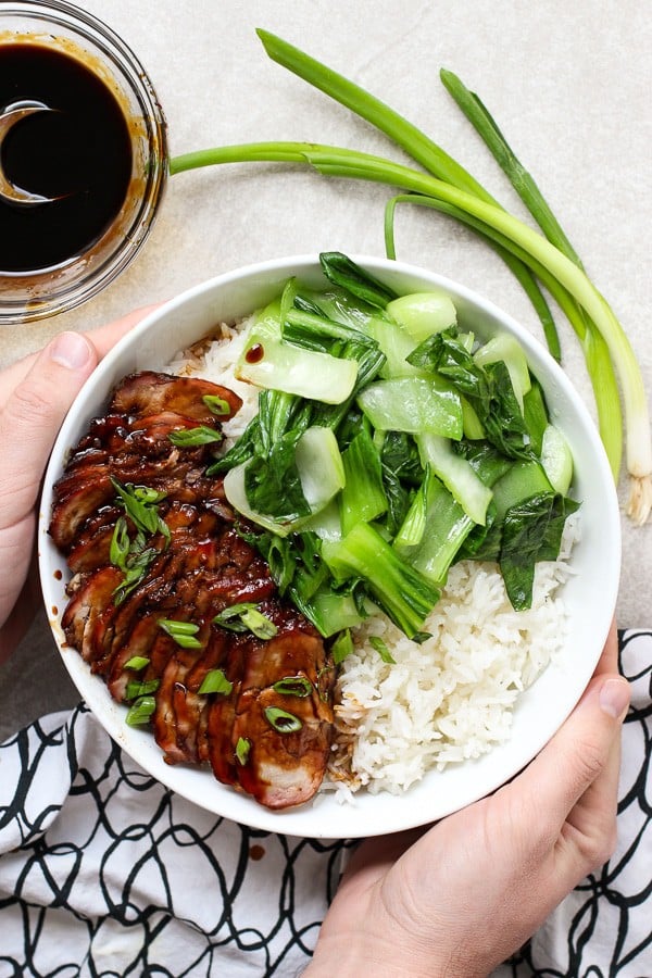 Hands holding Chinese Barbecue Pork (char Siu) and Bok Choy Rice Bowl