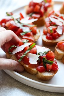 Hand grabbing a piece of Bruschetta with Tomatoes, Basil and Balsamic Vinegar