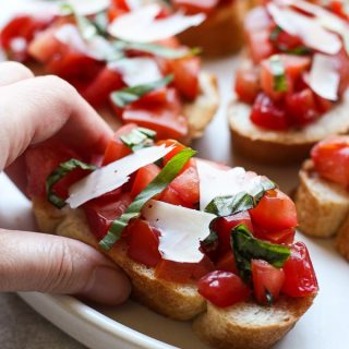 Hand grabbing a piece of Bruschetta with Tomatoes, Basil and Balsamic Vinegar