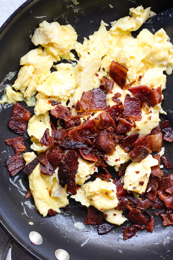 Scrambled eggs and bacon in a skillet
