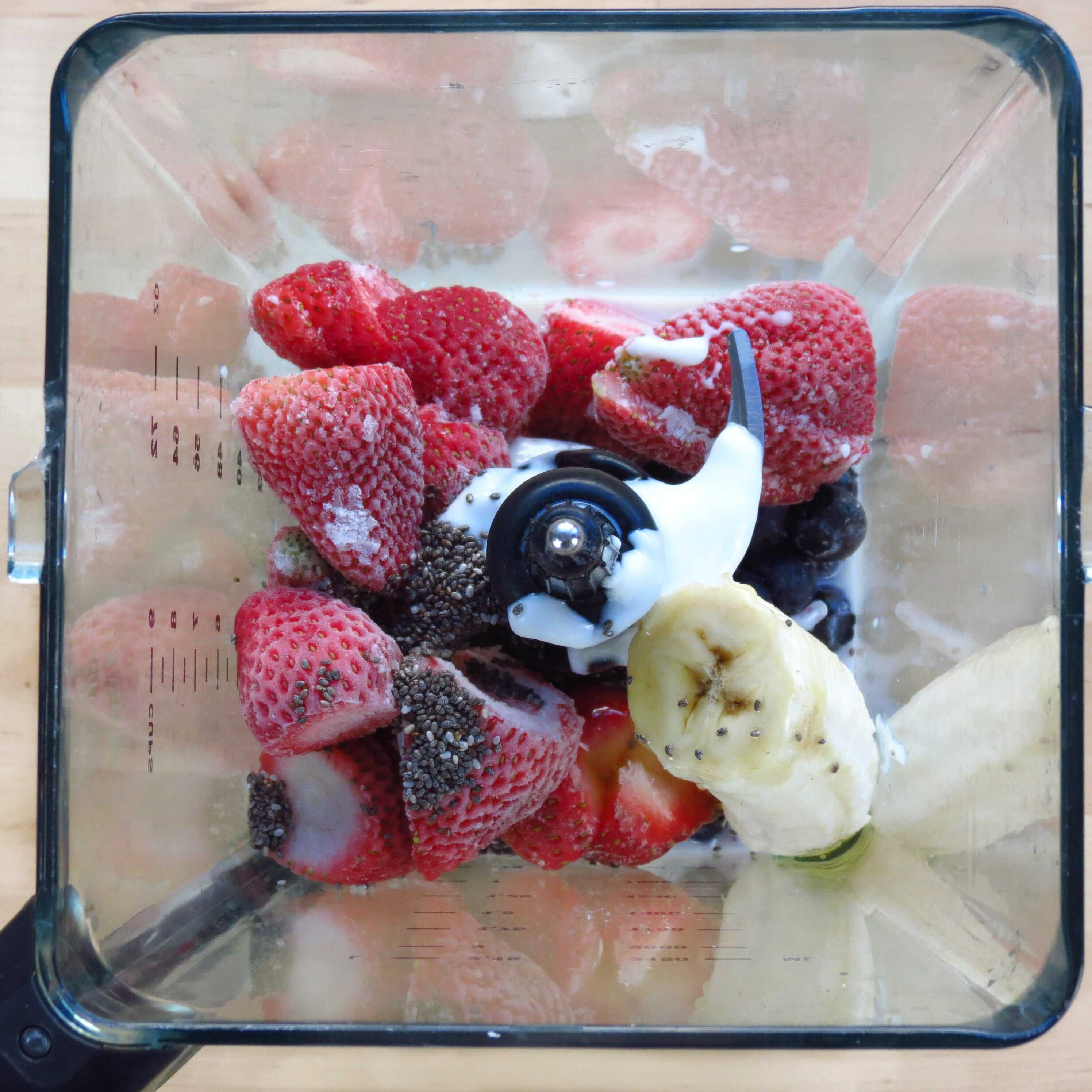 Blending strawberries, blueberries, banana, yogurt, milk, honey and chia seeds for Berry Banana Chia Smoothie