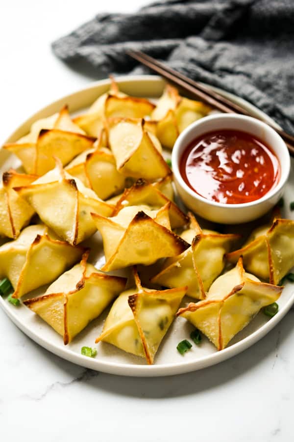 Baked Cream Cheese Wontons on a plate with a bowl of sweet chili sauce