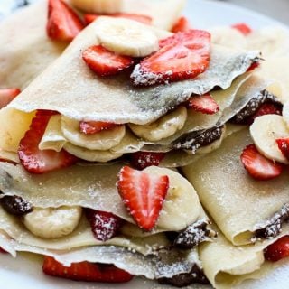 Strawberry Banana Nutella Crepes stacked on a plate