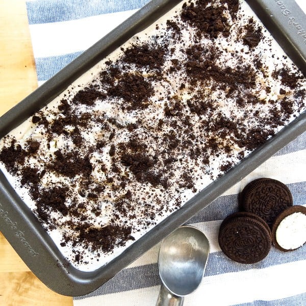 Closeup of a rectangular tub of cookies and cream ice cream, with oreo cookies next to it