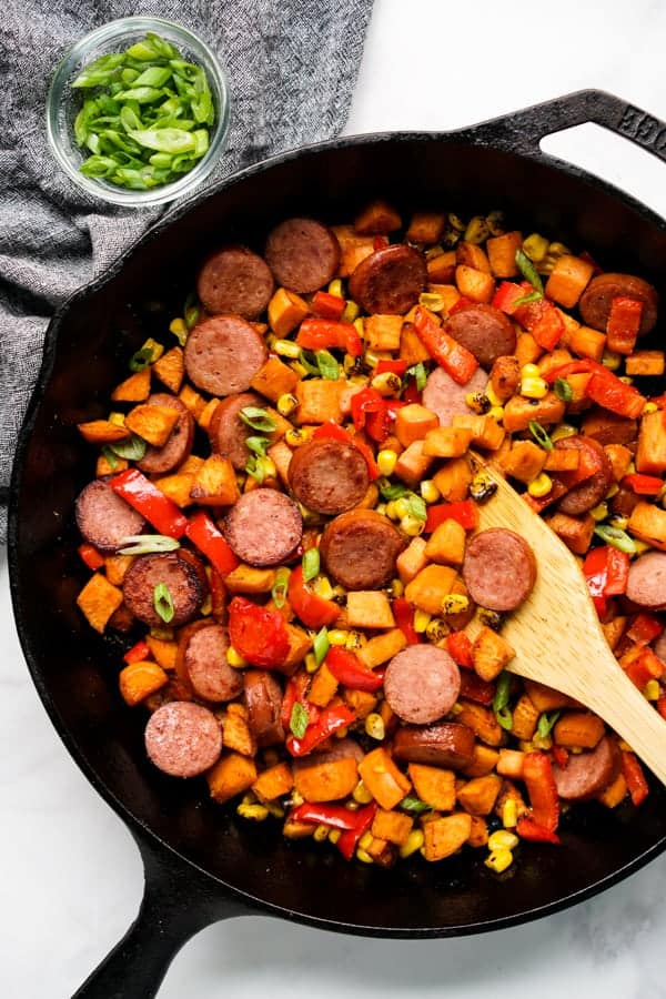 Sweet potatoes, bell peppers, corn and sausage in a skillet