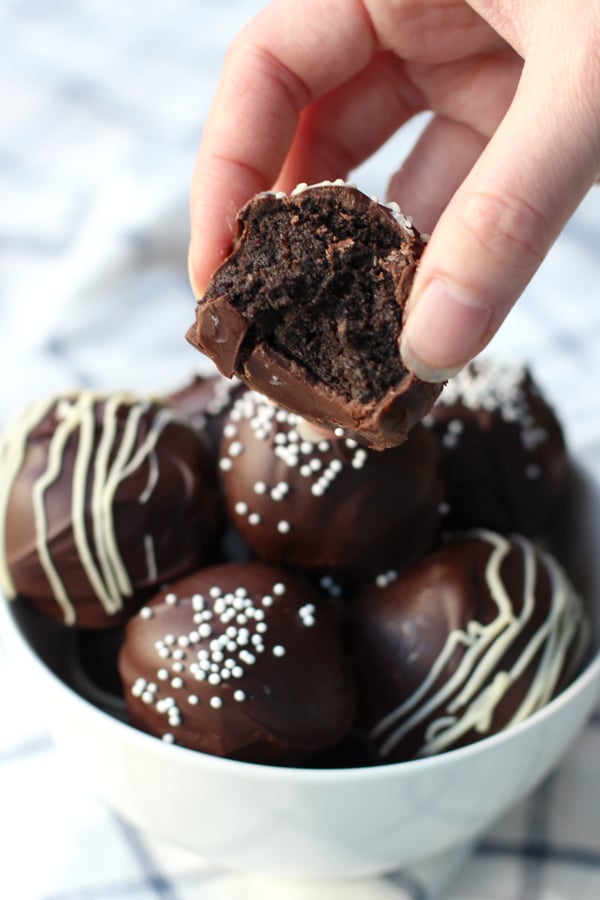 Finger picking up No-Bake Oreo Truffles from a bowl full of them