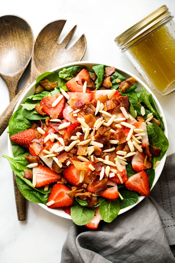 Top down look of Spinach Salad topped with bacon and strawberries and almonds, with Lemon Maple Dressing