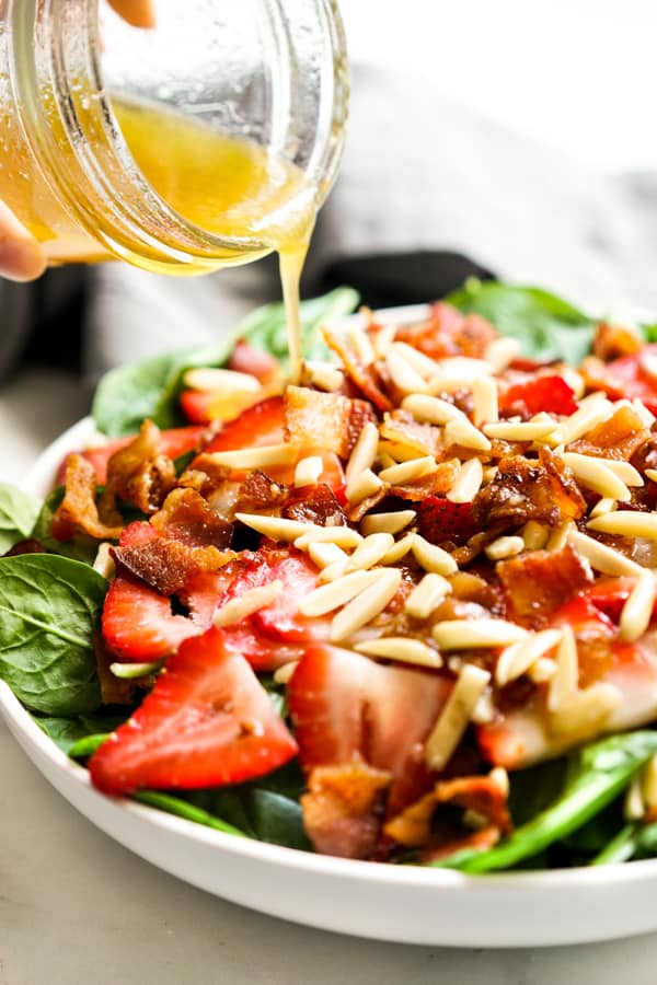 Pouring Lemon Maple Dressing onto Spinach Salad