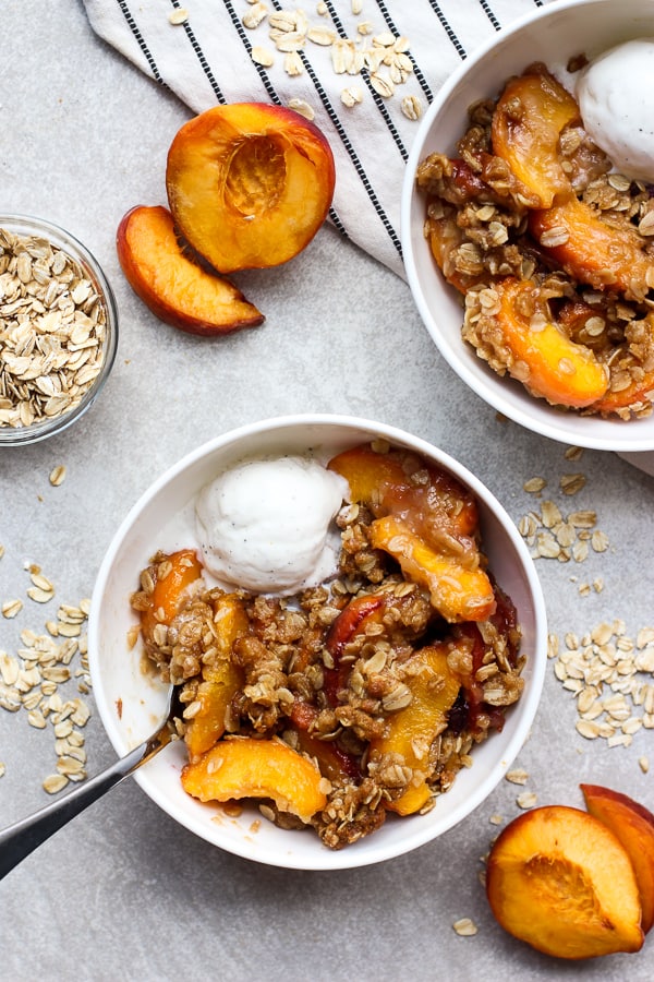 Two bowls of peach crisp with vanilla ice cream