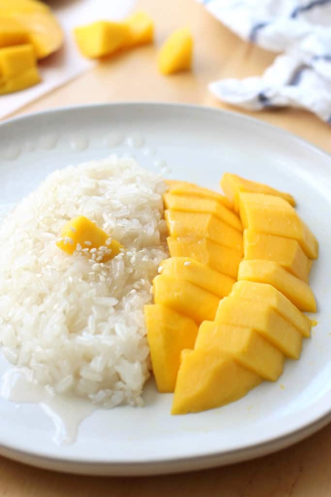 A plate of Thai mango sticky rice soaked in coconut