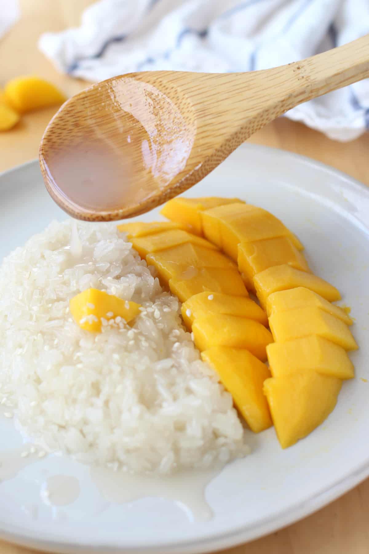 Dripping coconut sauce onto Mango and Sweet Sticky Rice on a plate