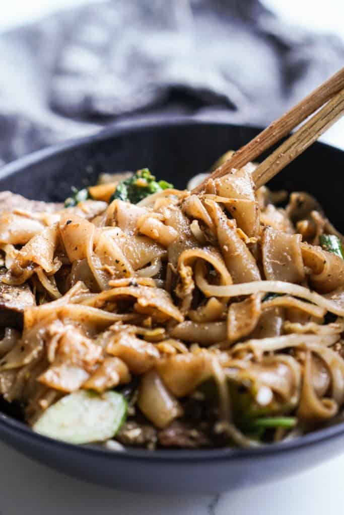 Picking up pad see ew noodles with chopsticks