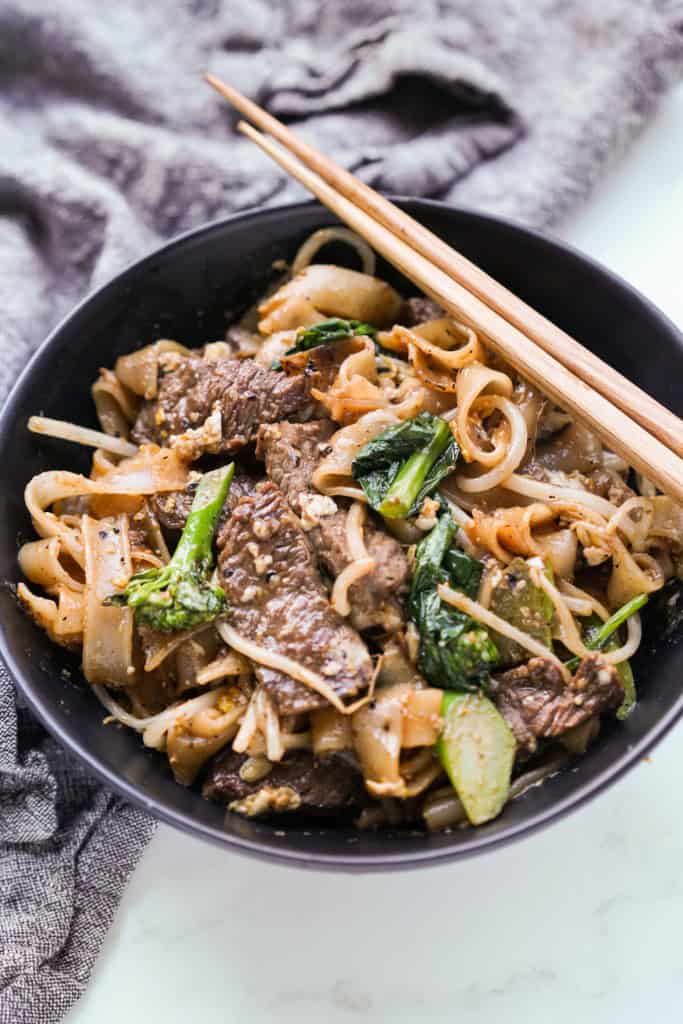 A bowl of pad see ew made with rice noodles, beef and Chinese broccoli
