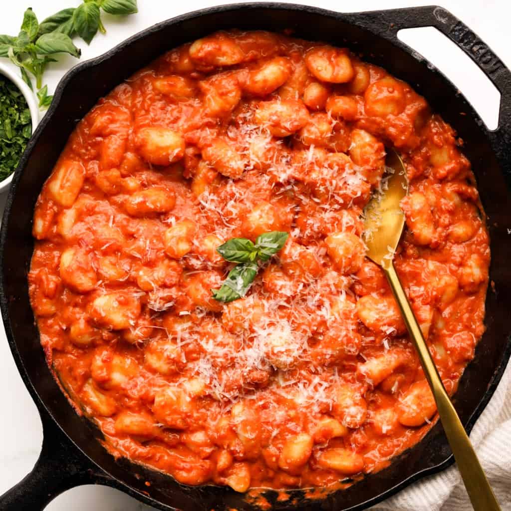 Gnocchi coated in creamy tomato sauce in a large cast iron skillet