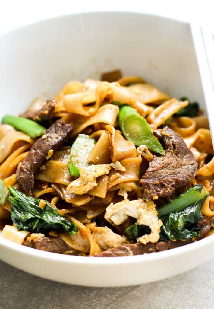 A bowl of Pad See Ew Noodles topped with eggs and chinese broccoli and beef