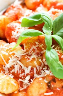 closeup of gnocchi in tomato sauce with basil on top