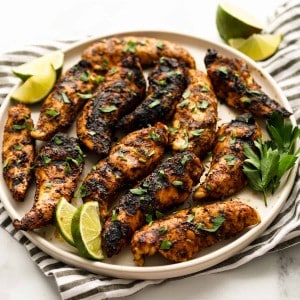 A plate of grilled cajun chicken garnish with parsley and lime