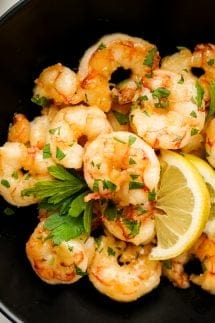 A plate of shrimp with lemon wedges