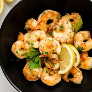 A plate of shrimp with lemon wedges