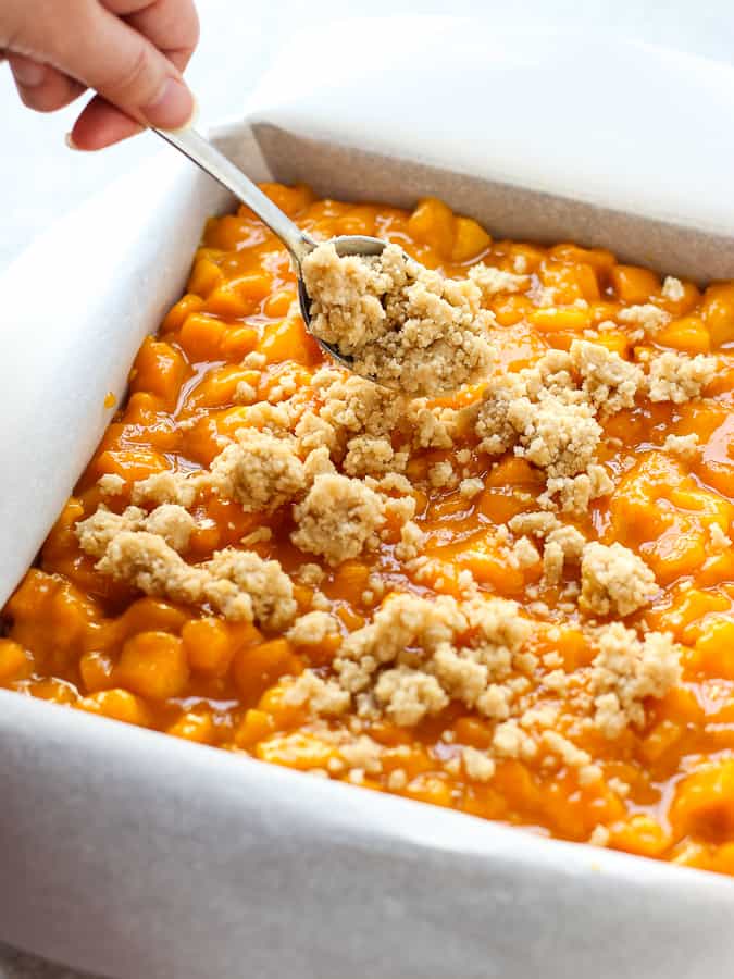 Spreading crumbles onto a pan of Mango Crumb Bars