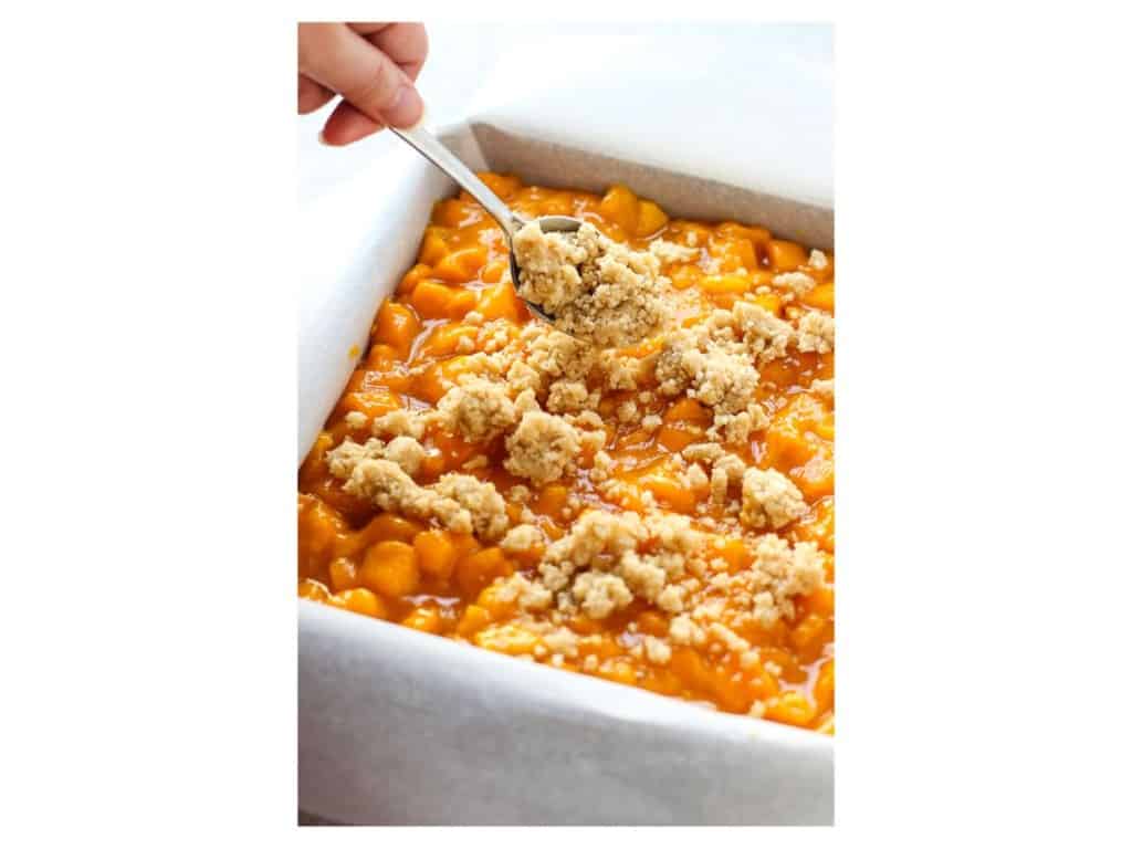 Sprinkling crumbles to top off the mango crumb bar