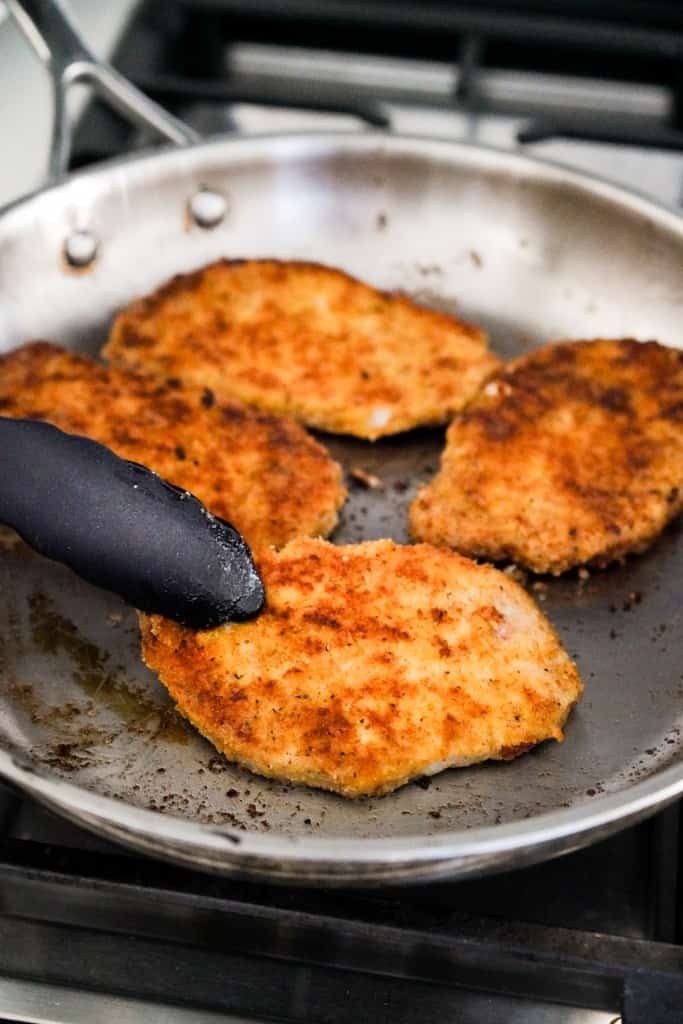 Searing breaded pork chops on a skillet