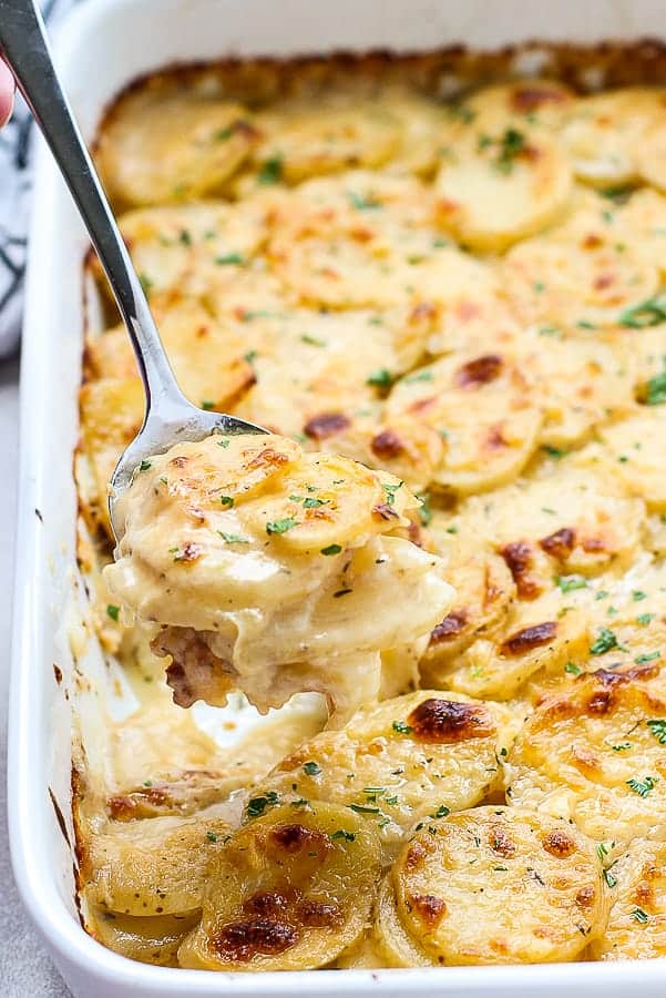 Scooping a spoonful of Cheesy Garlic Scalloped Potatoes