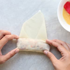 Rolling uncooked egg roll to close