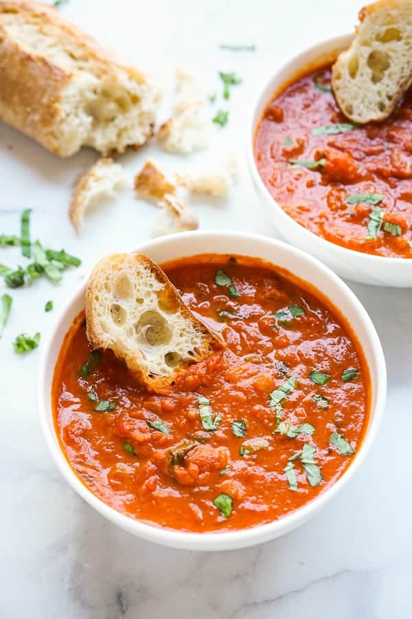 Two bowls of Simple Tomato Soup with baguettes dip into them