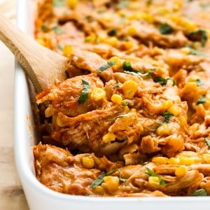 Digging into layers of chicken enchilada casserole using a wooden spoon