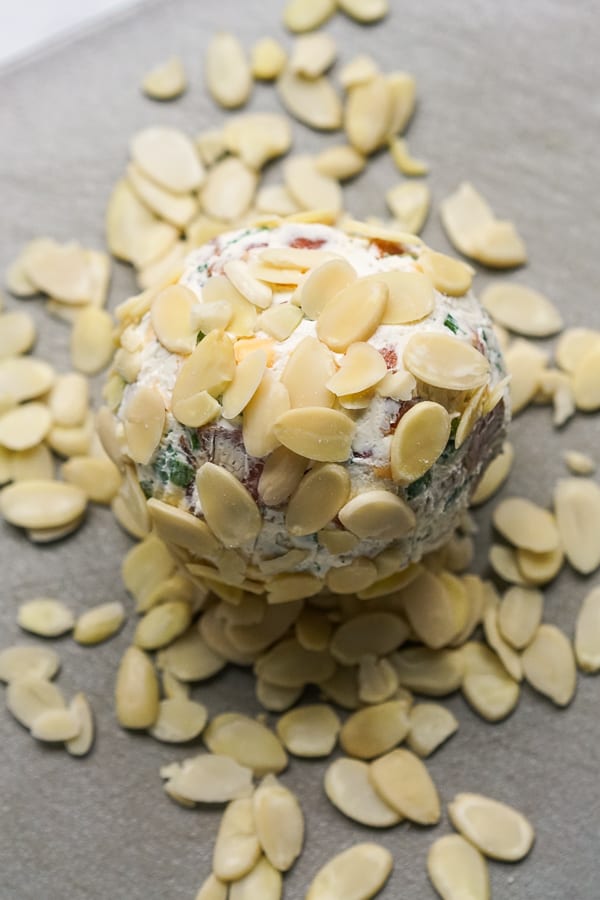 Making Bacon Ranch Cheeseball: coating cheeseball with shaved almonds