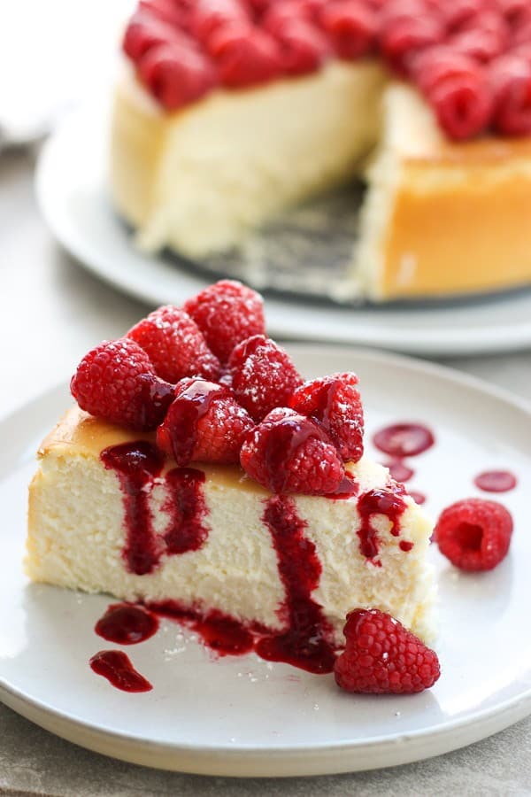 a slice of ricotta cheesecake topped with berries and sauce on a small plate