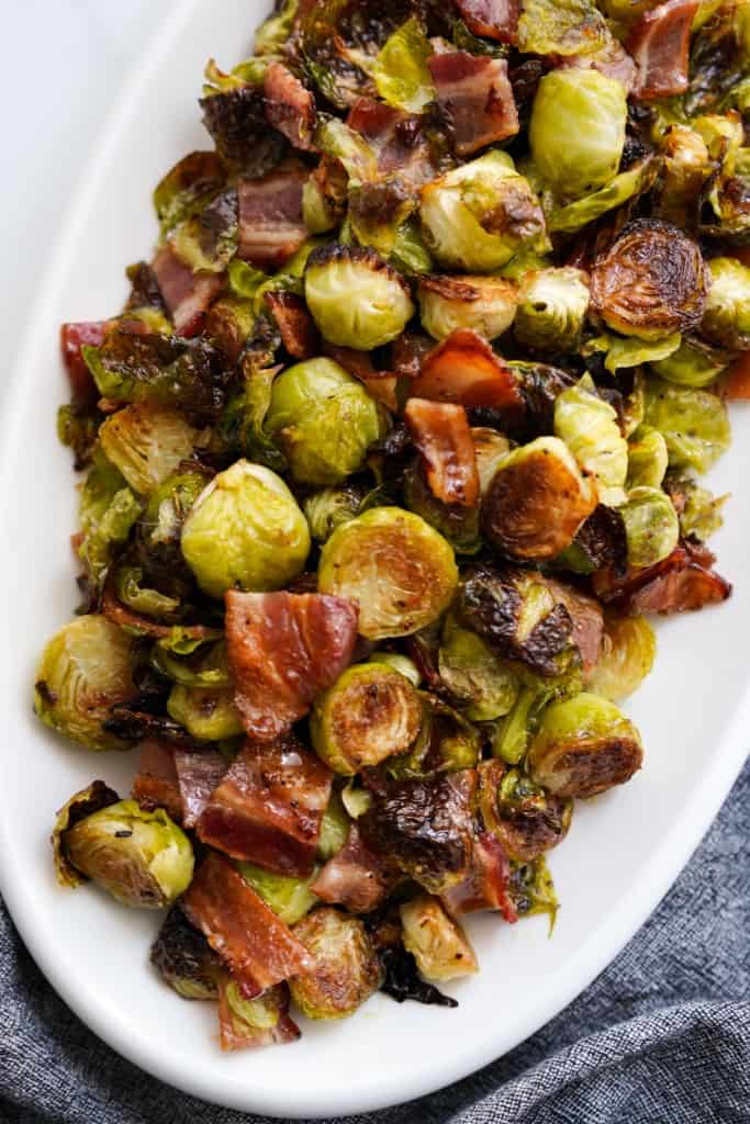 Close up of top down view of a plate of roasted Brussels sprouts tossed with bacon and garlic