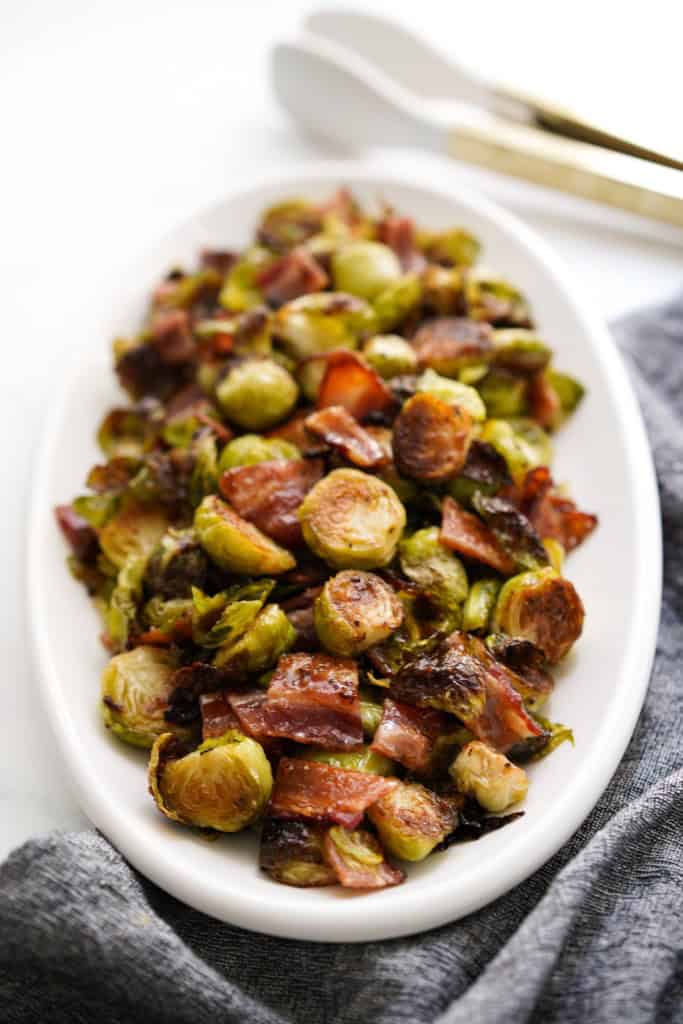 Close up view of an oval plate with Brussels sprouts tossed in bacon and honey