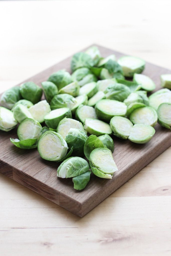 Fresh Brussels sprouts sliced in halves on a wooden cutting board