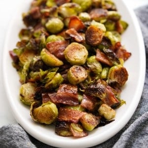 Closeup of a plate loaded with roasted brussels sprouts with bacon and honey