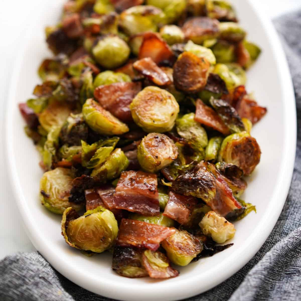 Closeup of a plate loaded with roasted brussels sprouts with bacon and honey