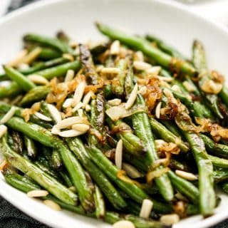 A plate of charred green beans topped with Caramelized Onions