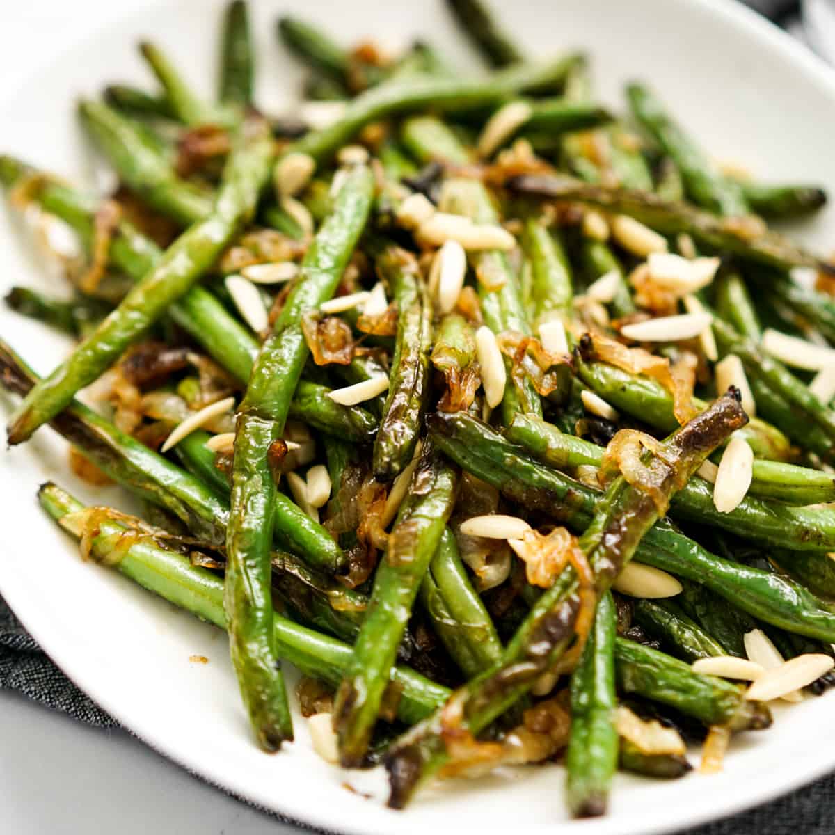 A plate of green beans topped with caramelized onions