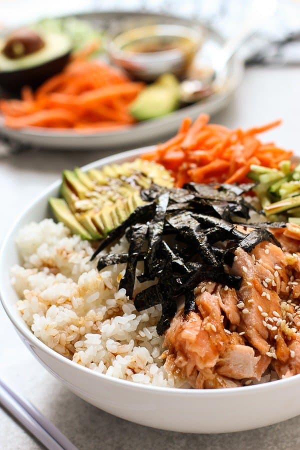 Deconstructed Baked Salmon Sushi Bowl with garnishes in the background