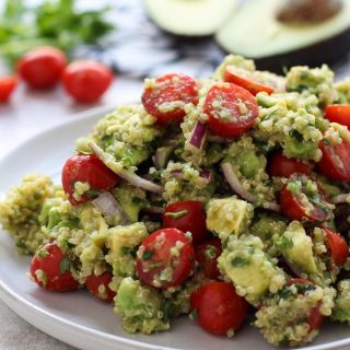 A plate of Avocado Quinoa Salad with avocados and tomatoes in the background