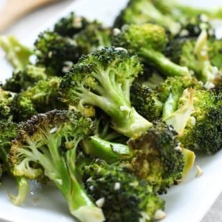 Roasted Lemon Garlic Broccoli on a rectangular plate with lemons behind