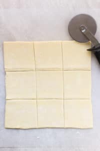 Cutting puff pastry into 9 squares for Sausage and Cheese Puff Pastry Pockets