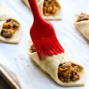 Brushing egg wash onto Sausage and Cheese Puff Pastry Pockets