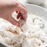 Coating chicken in flour mixture to make Sweet and Sour Chicken