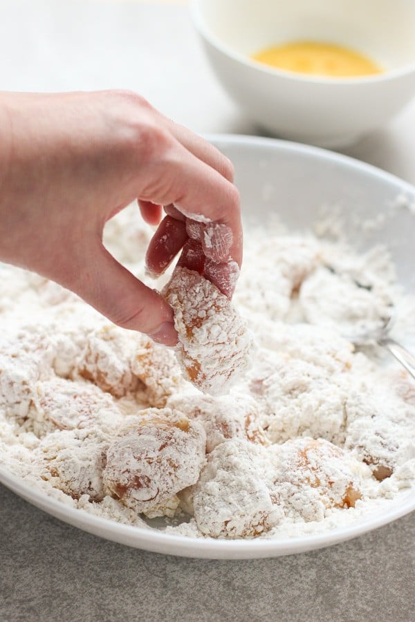 Coating chicken in flour mixture to make Sweet and Sour Chicken