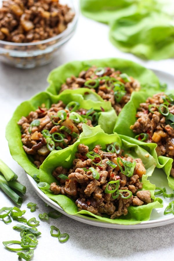 A plate of Asian Lettuce Wraps with a bowl of ground pork and lettuce in the background